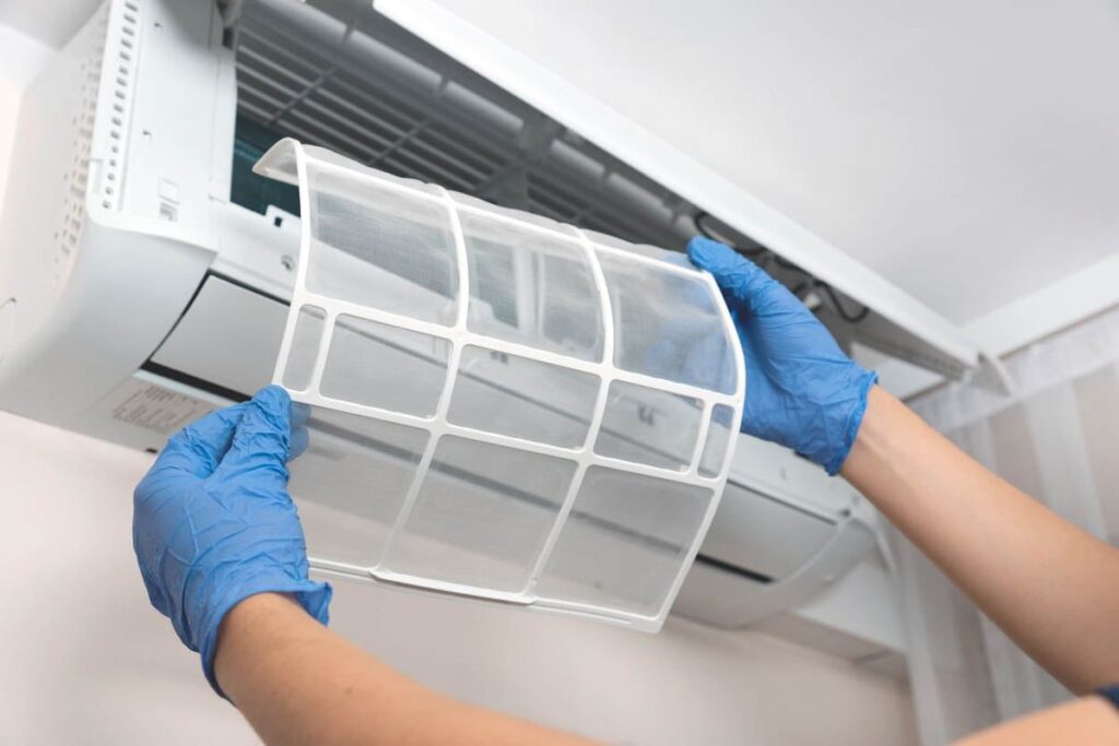 Homeowner replacing HVAC air filter as part of DIY maintenance between professional annual service visits 