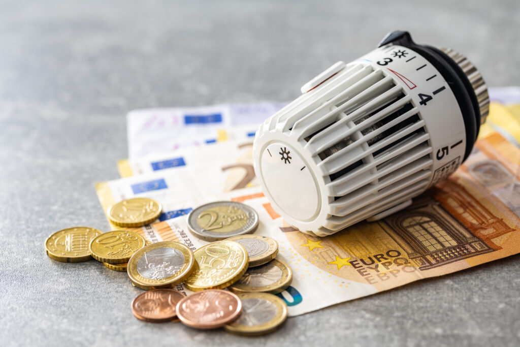 Thermostatic valve placed on euro banknotes symbolizing energy costs and savings.